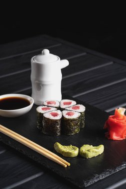 Japon menüsü. Siyah arka planda suşi yuvarlanıyor..