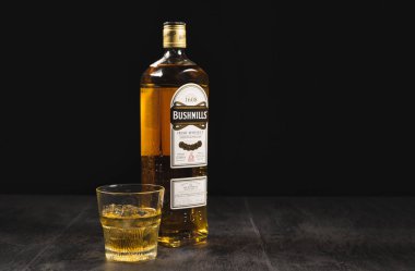 Kiev, Ukrayna - 02 Kasım 2018. Bushmills viski şişesi taş masada ve siyah arka plan başyazısında. Bushmills İrlanda 'nın en eski viski fabrikasıdır. 1784 'te kuruldu..