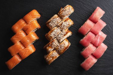 Japon menüsü. Siyah arka planda suşi yuvarlanıyor..