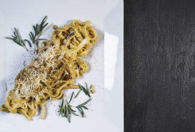 Beyaz bir tabakta siyah bir masa üzerinde nefis bir makarna.