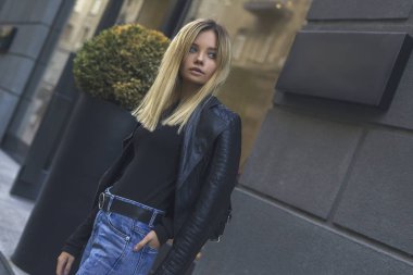 Şehir caddesinde yürüyen, günlük giysiler içinde şık bir kadın. Mağaza arka planında modaya uygun kız modelinin moda portresi