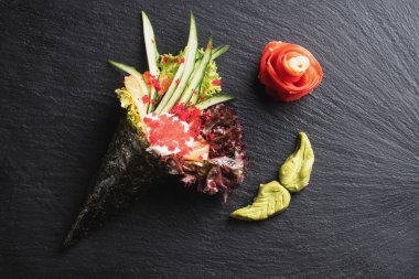 Somon, karides ve sebzeli farklı türde suşi ruloları. Siyah arkaplanda