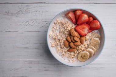 Diyet kahvaltı. Beyaz arka planda meyve ve fındıklı ev yapımı yulaf ezmesi. Üst görünüm