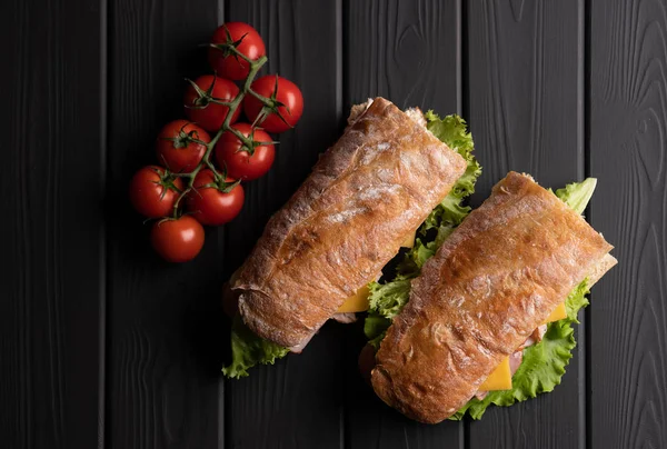 Vegetarian baguette sandwich on wooden dark background. Kitchen. Delicious bread. Food. Top view