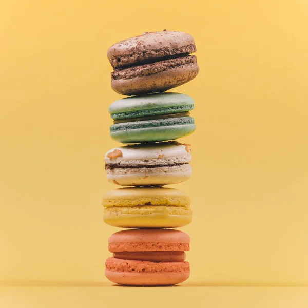Traditional french dessert of colorful macaron set on yellow background. Delicious sweet food.