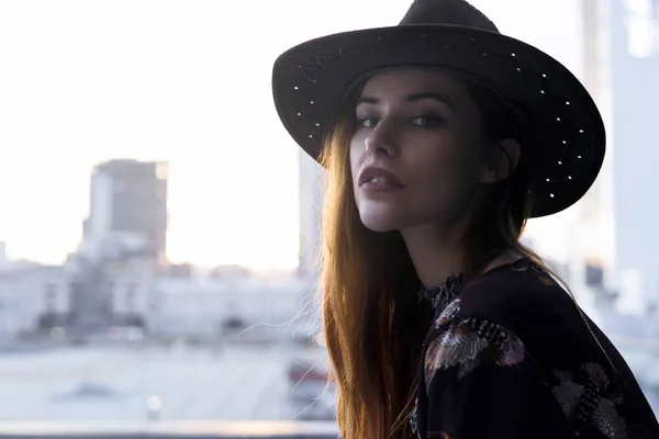 Street style fashion woman in a hat posing on street. Fashionable girl portrait on building background