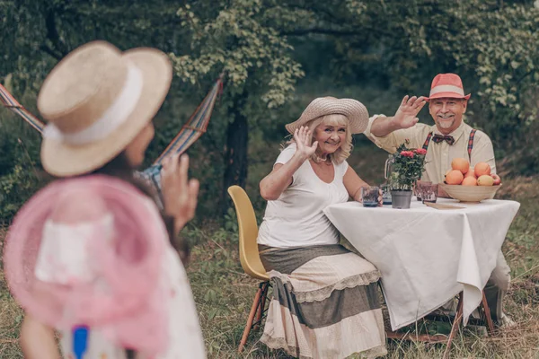 Šťastná Babička Dědeček Sedí Stolu Popíjejí Limonádu Mávají Svou Vnučku — Stock fotografie