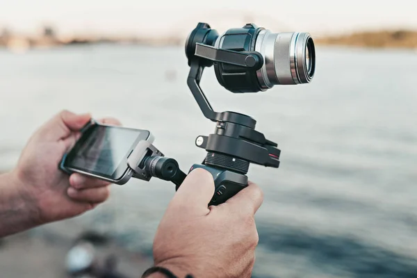 Record technology. Cinematic digital equipment. Camera. Hand with smartphone traveling video camera with stabilizer