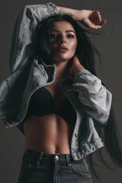 ジーンズとジーンズのジャケットでエレガントなヌード魅力的な女の子の肖像画 セクシーファッションスタイル女性モデルPosing上の黒背景でスタジオ — ストック写真