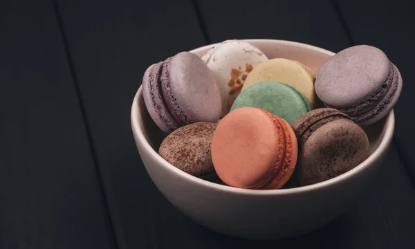 Traditional french dessert of colorful macaron set on black table background. Delicious sweet food.