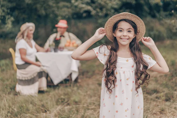 Happy Young Granddaughter Posing Foreground Sundress Hat Park Old Grandparents Royalty Free Stock Photos