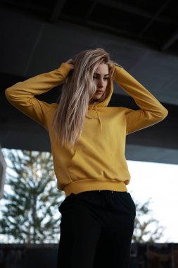 Şık, seksi spor kızı portresi ceketli, pantolonlu, arka planda poz veren spor ayakkabılı. Sokakta modaya uygun bir kadın model.