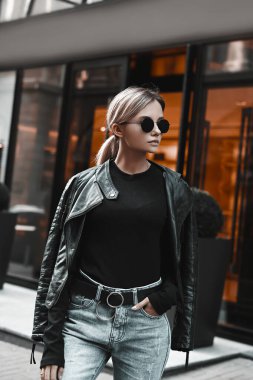 Mağazanın arka planında günlük kıyafetlerle poz veren şık bir kadın. Moda kızı modelinin sokaktaki şehir portresi.