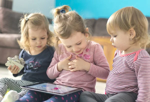 Tři Sestřičky Používání Tabletu Doma Sedět Uprostřed Hračky Sledovat Něco Stock Obrázky