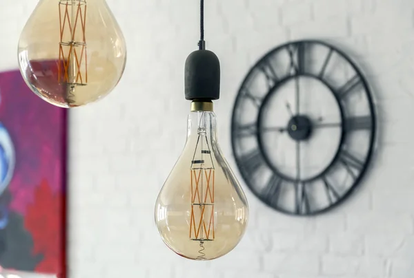 Decorative antique edison style light bulbs against brick wall background and clock