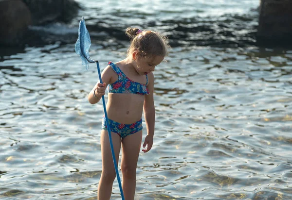 Kleines Mädchen steht mit Fischernetz Stockbild