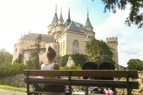 妈妈坐在长椅上，背靠美丽的城堡. — 图库照片