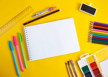 Sarı arkaplan görünümlü boş beyaz not defteri ve kırtasiye kağıdı. Okul ve öğrenme konsepti.