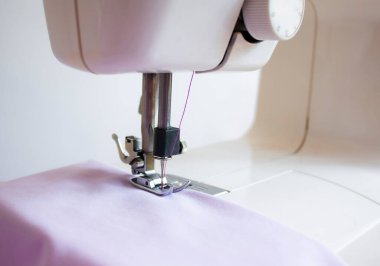 Kumaş, elektrikli dikiş makinesinin çalışma alanında bulunur.