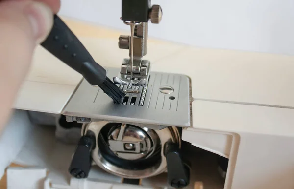 Elektrikli dikiş makinesinin parçalarını temizlemek. Dikiş makinesinin ipliği için makarayla ayak ve kancaya basın.