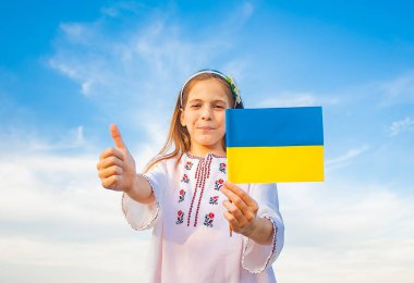 Ukrayna işlemeli gömlek giymiş bir kız Ukrayna bayrağını taşıyor.