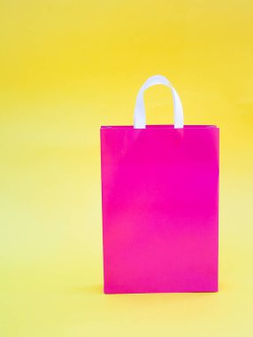 metin veya logo için yer ve boşluğu kopyalayan sarı arkaplan üzerinde pembe kağıt paket