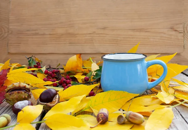 Kupa sonbahar yapraklarıyla masanın üstünde.