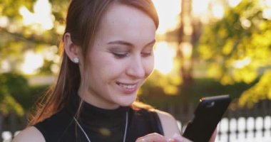 Akıllı Telefon kullanan genç bir kadın, şehirde cep telefonu olan çekici bir kadın. Mercek Fişeği.