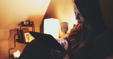 Geceleri Tablet Bilgisayar kullanan bir kadın. Yavaş hareket et. 4K DCI. Genç milenyum tüketicisi evden online alışveriş yapıyor, yatakta yatıyor. Günlük yaşamda teknoloji. Doli Vuruşu.