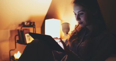 Geceleri Tablet Bilgisayar kullanan bir kadın. Yavaş hareket et. 4K DCI. Genç milenyum tüketicisi evden online alışveriş yapıyor, yatakta yatıyor. Günlük yaşamda teknoloji. Doli Vuruşu.