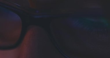 Gece Kadın Gözlüklü Tablet Bilgisayar ekranının yansıması. Yavaş hareket et. 4K DCI, Dolly shot. Dijital tablet kullanan, internette gezinen, film izleyen bir kadın. Gözlüklerdeki ışık yansımaları.