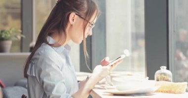 Kadın Elleri Kafede Akıllı Telefon Kullanıyor. Yavaş hareket, dengeleyici. İş kadını bir kafede sosyal medyada mesajlaşıyor, iletişim kuruyor, internette çalışıyor, interneti arıyor, öğreniyor.