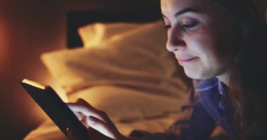 Geceleri Tablet Bilgisayar kullanan bir kadın. Yavaş hareket et. 4K DCI. Genç milenyum tüketicisi evden online alışveriş yapıyor, yatakta yatıyor. Günlük yaşamda teknoloji.