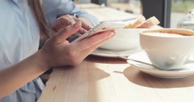 Kadın Elleri Kafede Akıllı Telefon Kullanıyor. Yavaş hareket, dengeleyici. İş kadını bir kafede sosyal medyada mesajlaşıyor, iletişim kuruyor, internette çalışıyor, interneti arıyor, öğreniyor.