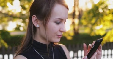 Akıllı Telefon kullanan genç bir kadın, şehirde cep telefonu olan çekici bir kadın. Mercek Fişeği.