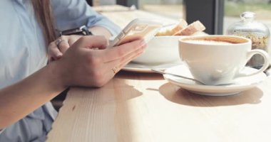 Kadın Elleri Kafede Akıllı Telefon Kullanıyor. Yavaş hareket, dengeleyici. İş kadını bir kafede sosyal medyada mesajlaşıyor, iletişim kuruyor, internette çalışıyor, interneti arıyor, öğreniyor.