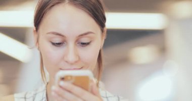 İş kadını portresi. Ortak Çalışma Alanında Akıllı Telefon Kullanıyor. Yakın plan. 4K Yavaşlama Hareketi, DCI. Modern cam binada cep telefonu kullanan çekici bir kadın. İletişim ve Teknoloji