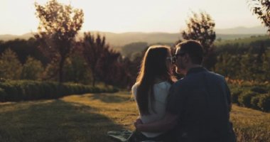 Günbatımında Peri Masalı Bahçesinde Gelecek Hakkında Genç Bir çift Rüyası. Yavaş haraket 4K. Romantik Adam ve Kadın öpüşüp hayat planlarını paylaşıyorlar. Yeni Aile. Sevgi ve şefkat. Sinematik çekim, mercek parlaması.
