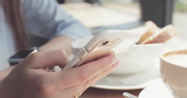 Kadın Elleri Kafede Akıllı Telefon Kullanıyor. Yavaş hareket, dengeleyici. İş kadını bir kafede sosyal medyada mesajlaşıyor, iletişim kuruyor, internette çalışıyor, interneti arıyor, öğreniyor.