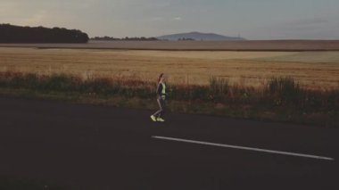 Koşucu kadın dışarıda koşuyor. Güneşli yolda antrenman yaparken çıplak ayaklı spor ayakkabısı giyen bir kadın. Ağır çekim. Mercek Fişeği