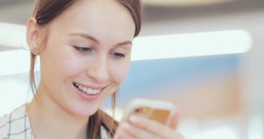 İş kadını portresi. Ortak Çalışma Alanında Akıllı Telefon Kullanıyor. Yakın plan. 4K Yavaşlama Hareketi, DCI. Modern cam binada cep telefonu kullanan çekici bir kadın. İletişim ve Teknoloji