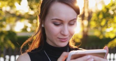 Akıllı Telefon kullanan genç bir kadın, şehirde cep telefonu olan çekici bir kadın. Mercek Fişeği.