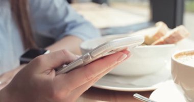 Kadın Elleri Kafede Akıllı Telefon Kullanıyor. Yavaş hareket, dengeleyici. İş kadını bir kafede sosyal medyada mesajlaşıyor, iletişim kuruyor, internette çalışıyor, interneti arıyor, öğreniyor.