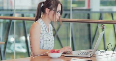 İş kadını, ortak çalışma alanında dizüstü bilgisayarda çalışıyor. 4K Yavaşlama Hareketi, DCI. Genç bir iş kadını, gözlük takıyor, modern ofis binasında taşınabilir bilgisayar kullanıyor. Hayatta Teknoloji