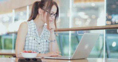 İş kadını, ortak çalışma alanında dizüstü bilgisayarda çalışıyor. 4K Yavaşlama Hareketi, DCI. Genç bir iş kadını, gözlük takıyor, modern ofis binasında taşınabilir bilgisayar kullanıyor. Hayatta Teknoloji