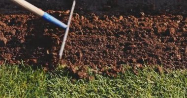 Bahçıvan bir tırmıkla toprağı temizliyor. Yavaş bir hareket yap. Tanımlanamayan insanların elleri toprağı düzleştiriyor, mükemmel çimler dikiyor, yeşil çimenler dikiyor. Manzara tasarımı üzerinde çalışan bir adam..