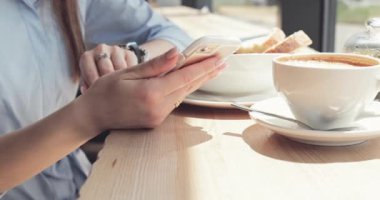 Kadın Elleri Kafede Akıllı Telefon Kullanıyor. Yavaş hareket, dengeleyici. İş kadını bir kafede sosyal medyada mesajlaşıyor, iletişim kuruyor, internette çalışıyor, interneti arıyor, öğreniyor.