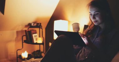 Geceleri Tablet Bilgisayar kullanan bir kadın. Yavaş hareket et. 4K DCI. Genç milenyum tüketicisi evden online alışveriş yapıyor, yatakta yatıyor. Günlük yaşamda teknoloji. Doli Vuruşu.