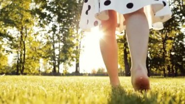 Şehir parkında Yeşil Çimlerde Yalınayak Yürüyen Kadın. 4K Yavaş Hareketi.