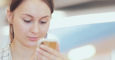 İş kadını portresi. Ortak Çalışma Alanında Akıllı Telefon Kullanıyor. Yakın plan. 4K Yavaşlama Hareketi, DCI. Modern cam binada cep telefonu kullanan çekici bir kadın. İletişim ve Teknoloji